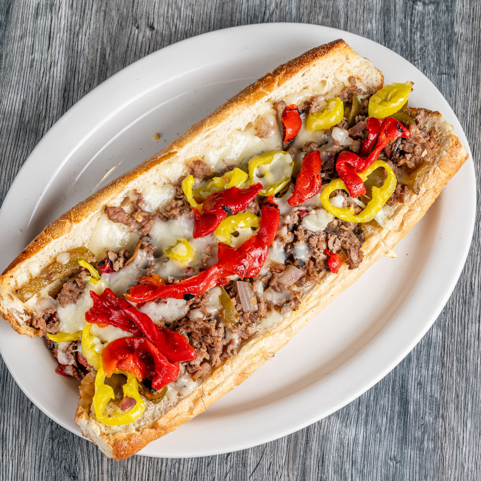 A Fantasy Pizza cheesesteak sub, filled with meat, melted cheese, and red and yellow peppers.